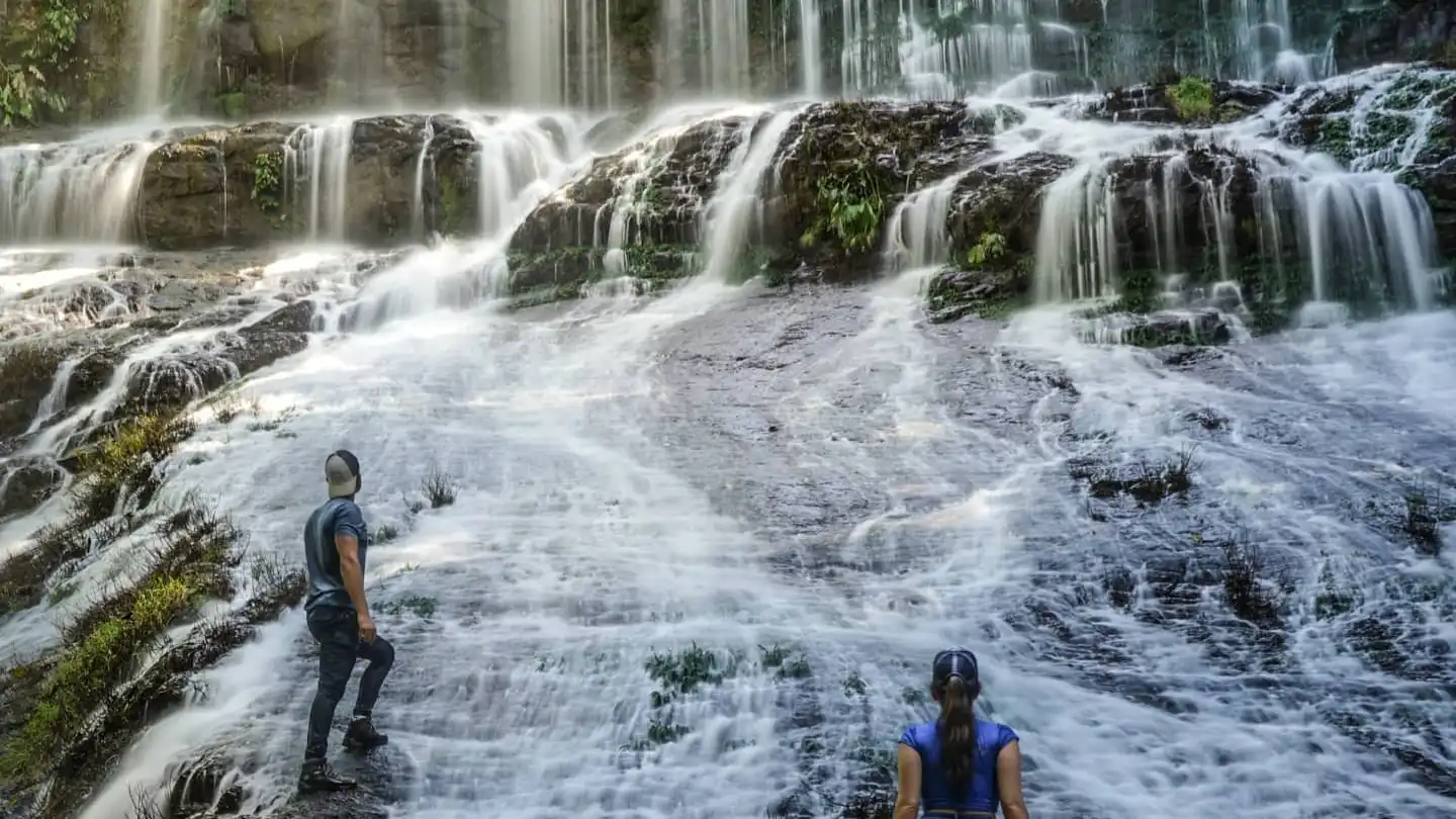 Two people standing in front of a waterfall