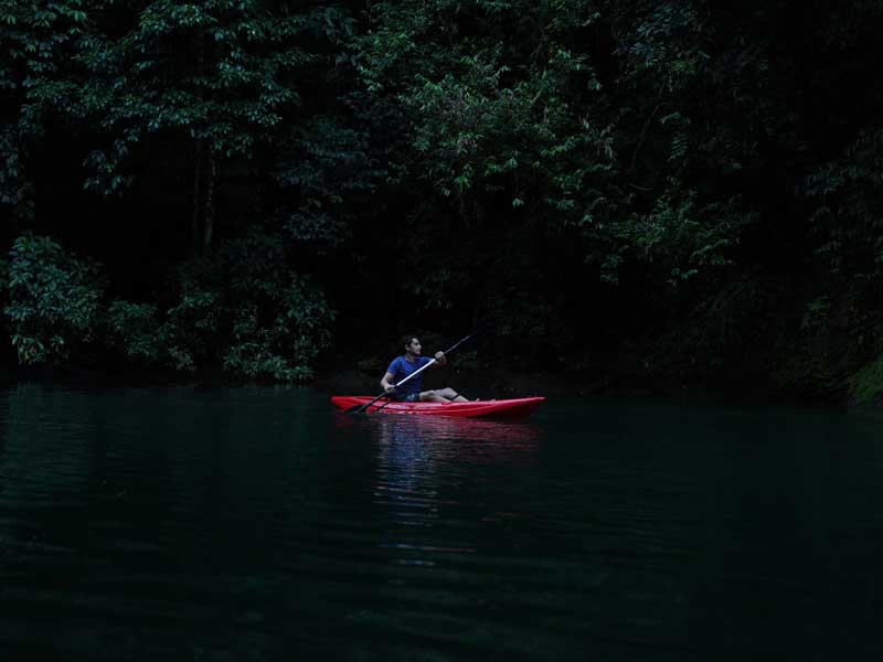 A man in a red kayak paddles through the water.