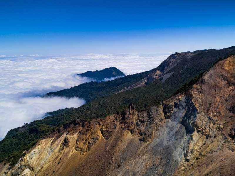 A view of the top of a mountain with clouds below.