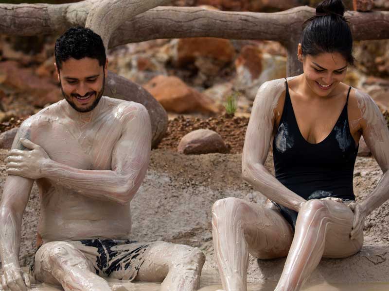 A man and woman covered in mud sitting on the ground.