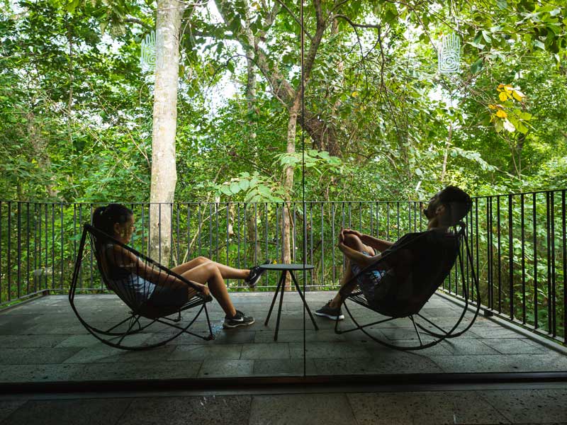 A couple of people sitting in chairs on a porch.